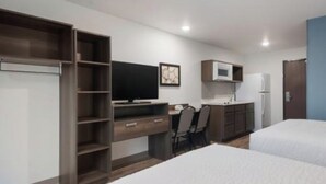 A hotel room with a bed, a desk with a computer, a television, a microwave, and a refrigerator. - Comfortable Suite w/ Kitchenette – Perfect for Extended Stay (Orlando)