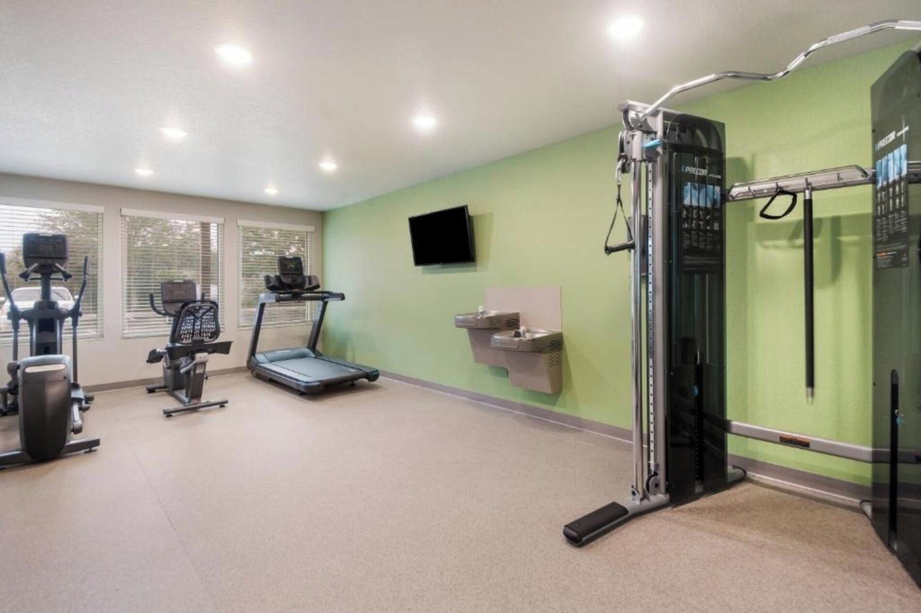 A gym with treadmills, elliptical machines, and a weightlifting station.