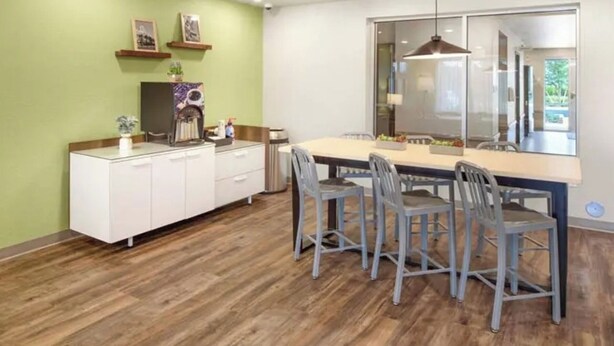 A modern kitchen with a dining area, featuring a large window and a view of the outdoors.