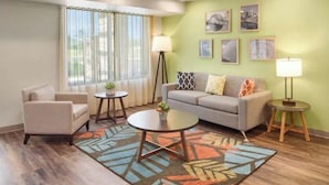 A modern living room with a sofa, armchair, coffee table, and two side tables. There are framed pictures on the wall and a floor lamp. - 3 Queen Studios with Kitchenette – Convenient, Clean, and Close to Attractions (Orlando)