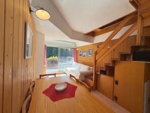 A wooden interior with a dining table, a sofa, and a staircase.