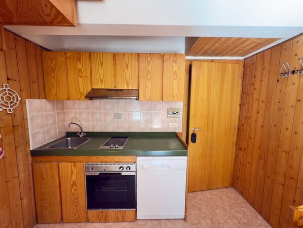 A compact kitchen with wooden cabinets, a sink, a stove, and a dishwasher.