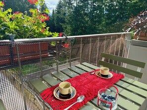 A balcony with a table set for two, a red tablecloth, and a glass of blueberries. - Ski-In/Ski-Out Flat w/ Balcony, Parking, Wi-Fi (Marilleva 1400)