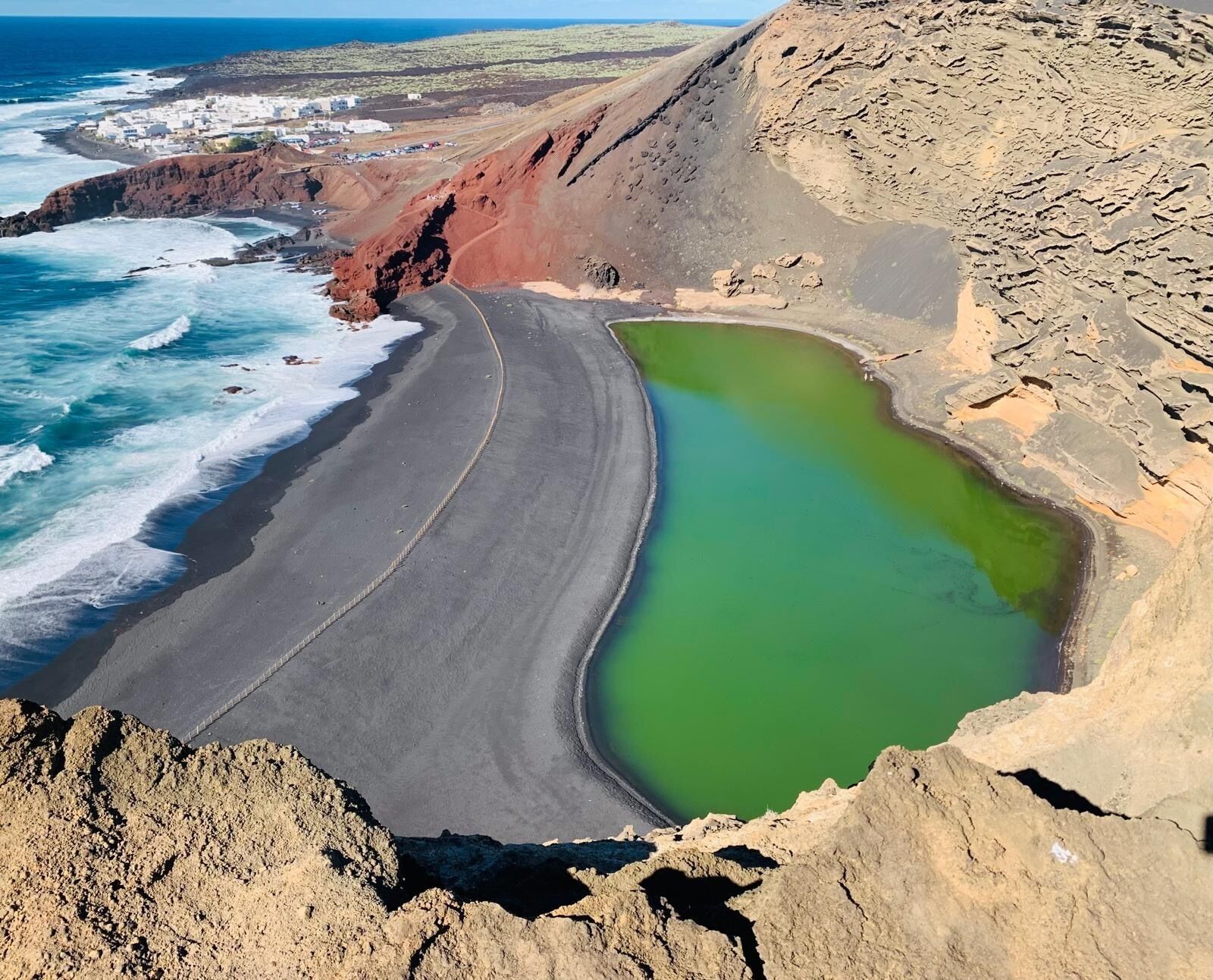 Una carretera costera serpentea a lo largo de una playa con una laguna verde.