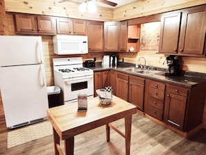 A kitchen with wooden cabinets, a white refrigerator, a stove, a microwave, and a coffee maker. - Hemlock Haven Cabin in the Woods (Vowinckel)