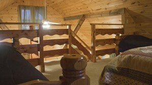 Puuinen mökki, jossa on kerrossängyt, portaat ja kattotuuletin.