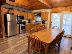 A kitchen with wooden cabinets, stainless steel appliances, and a dining table with chairs.