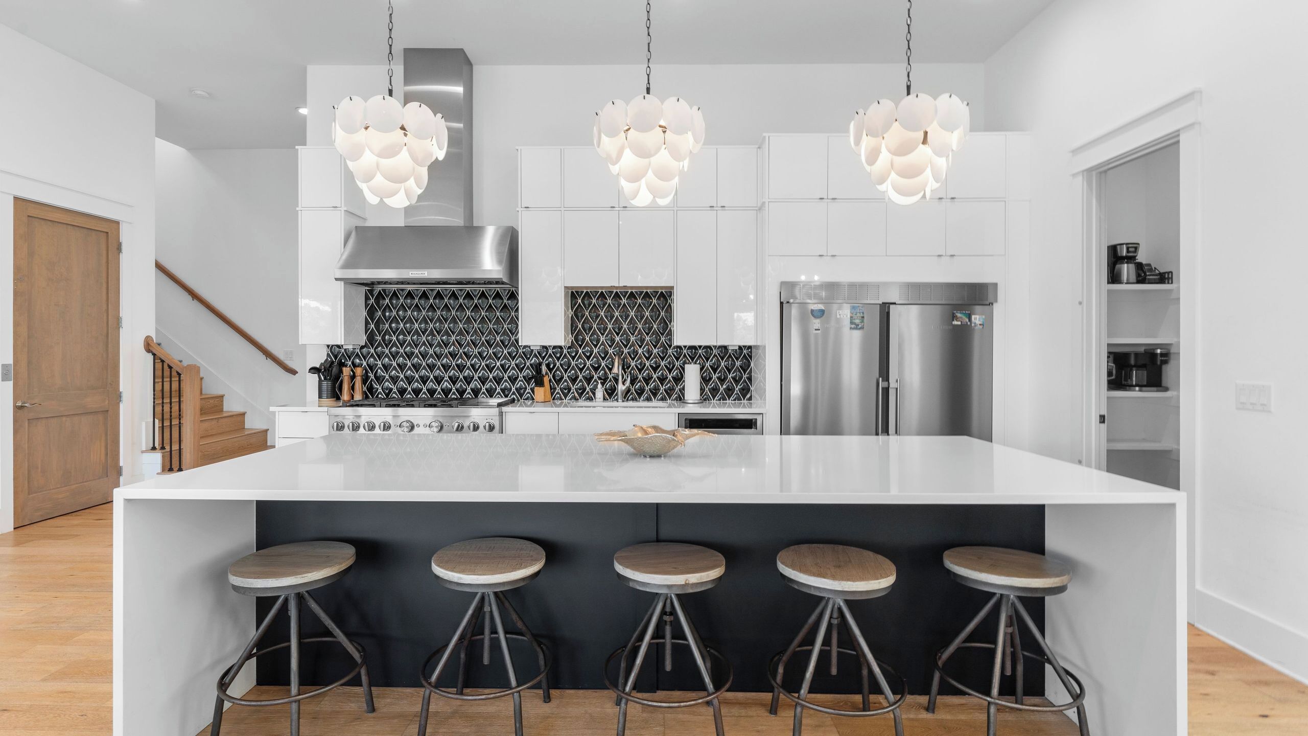Una cocina moderna con una isla central, electrodomésticos de acero inoxidable e iluminación colgante.