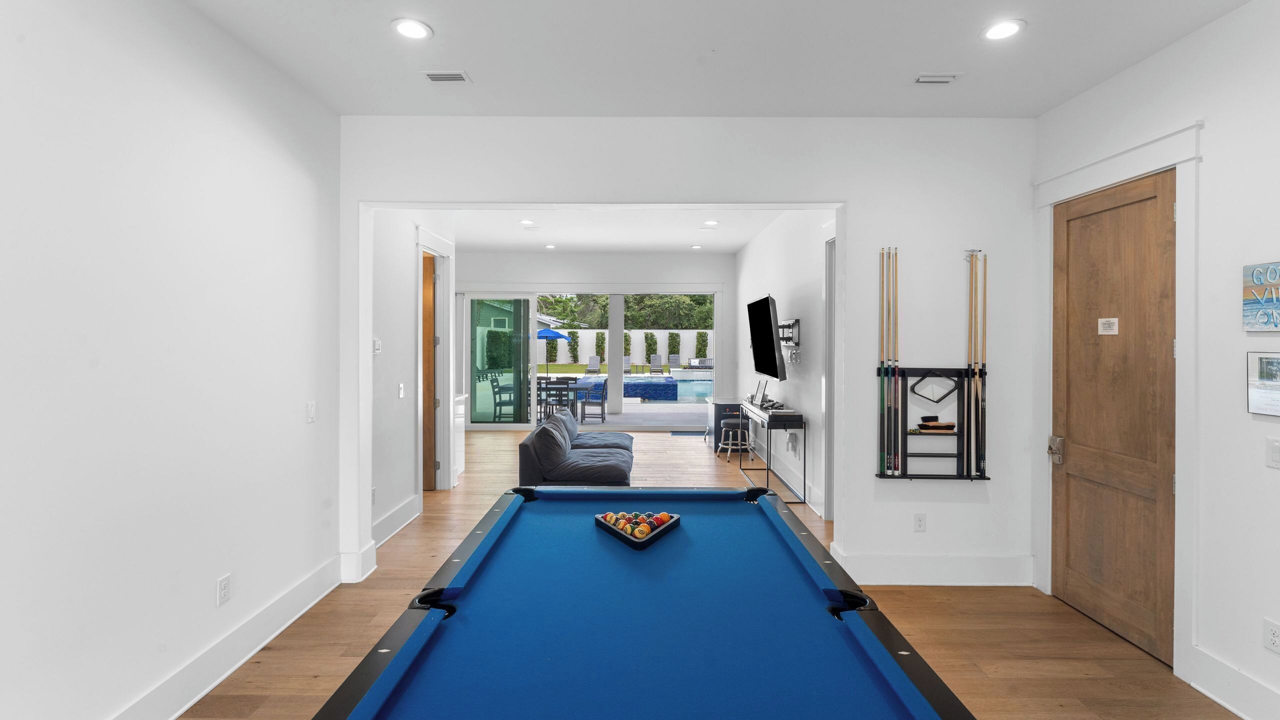 A pool table in a modern room with a view to an outdoor patio area.