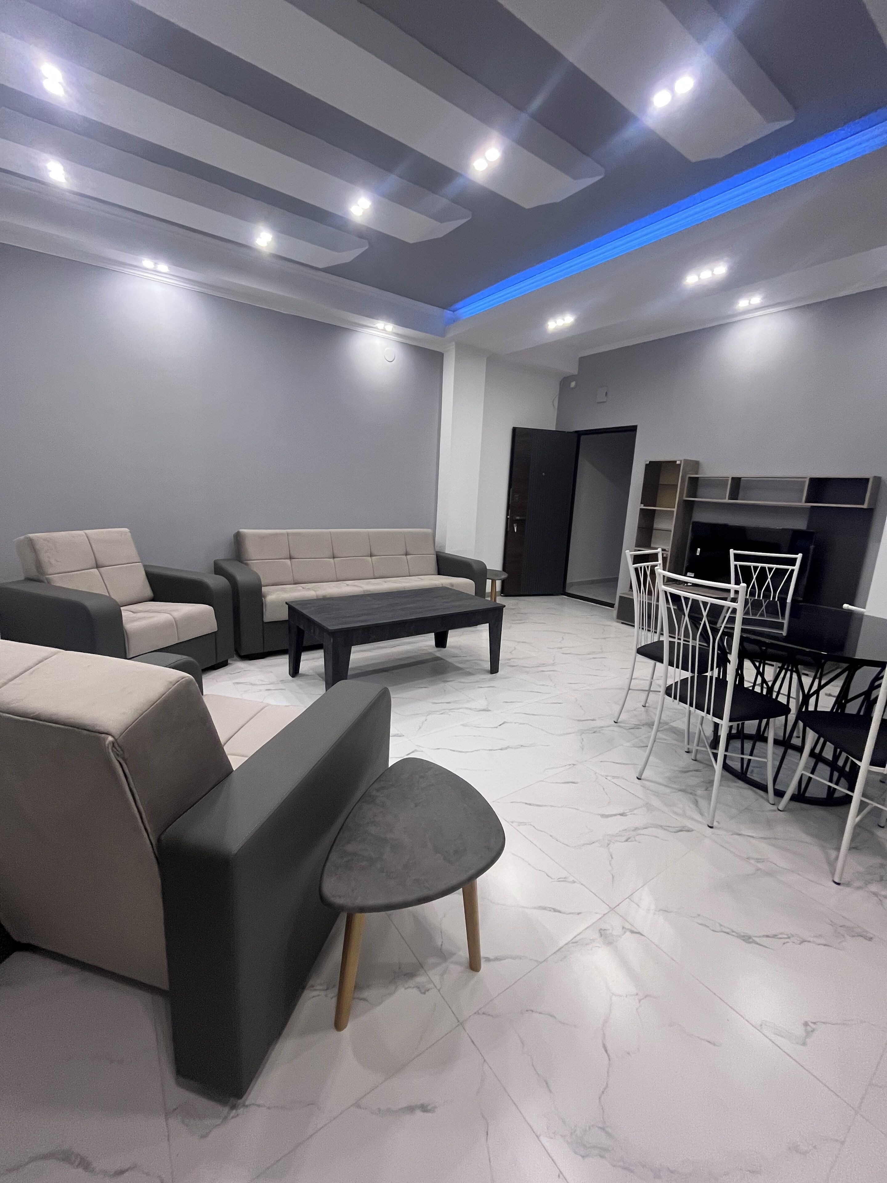 Un salon moderne comprenant un canapé, une table basse et un espace télévision avec un téléviseur à écran plat et une petite table.