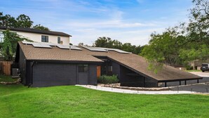 A modern house with a sloped roof, solar panels, and a well-maintained lawn. - Stylish Retreat, Shared Pool & Yard Near Downtown Fairlawn Lane A by Avantstay (Austin)