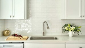 A kitchen with white cabinets, a stainless steel sink, a cutting board with fruits, and a vase of flowers. - Stylish Retreat, Shared Pool & Yard Near Downtown Fairlawn Lane A by Avantstay (Austin)