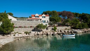 A stone house with a red-tiled roof, situated by a clear blue sea. - Villa Island Star with Pool (Milna)
