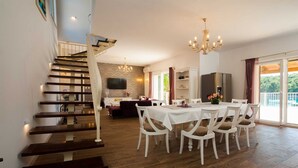 A spacious living area with a staircase, a dining table with chairs, a chandelier, and a television. - Villa Island Star with Pool (Milna)