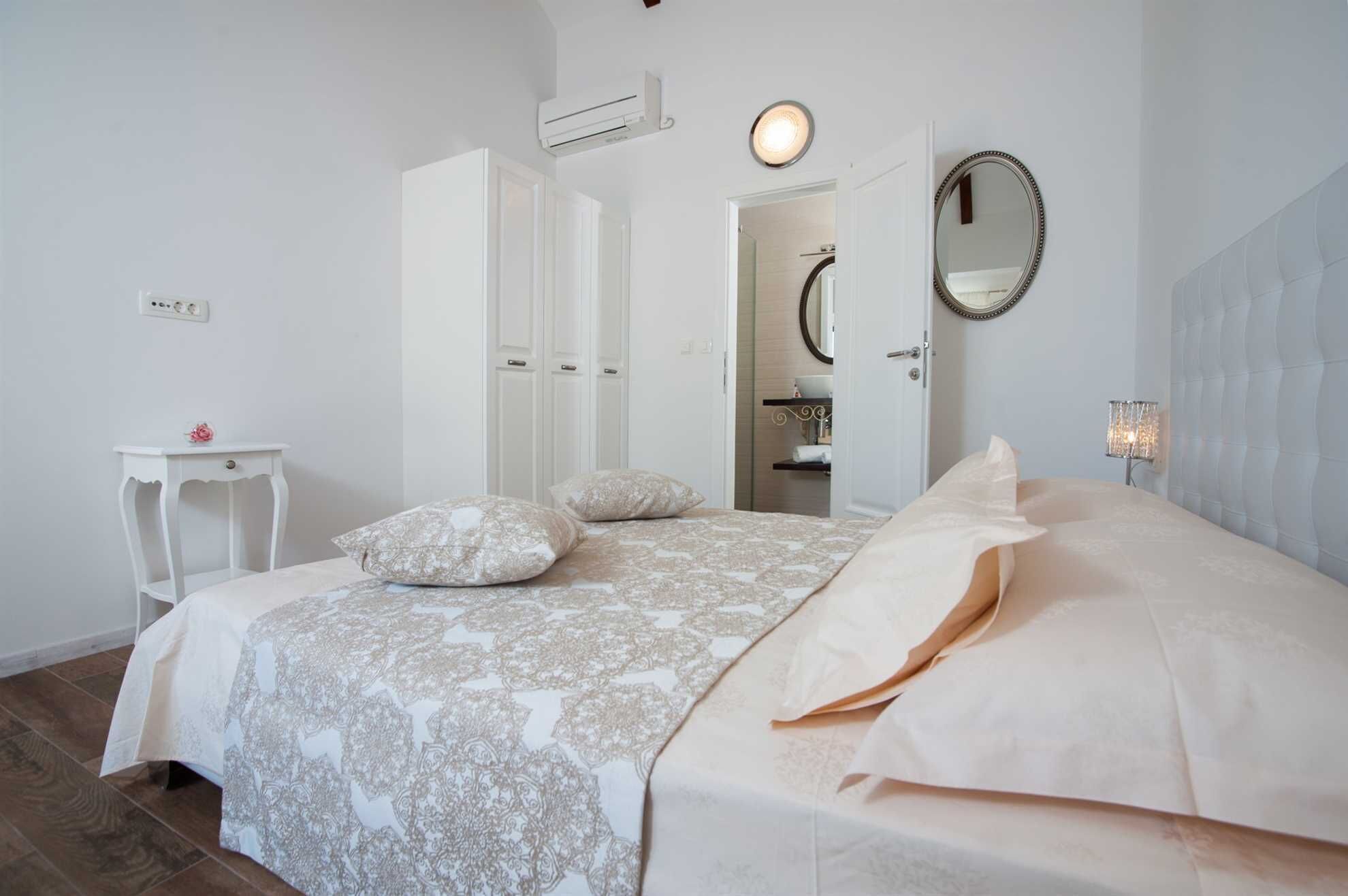 Une chambre à coucher comprenant un lit, une table de chevet, un miroir et un appareil de climatisation.