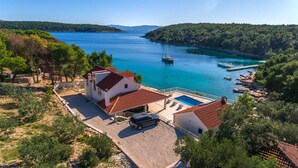 A coastal property with a swimming pool, a parked car, and boats in the background. - Villa Island Star with Pool (Milna)