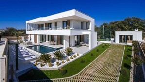 Una casa moderna de dos pisos amb piscina, mobiliari exterior i jardí ben cuidat.