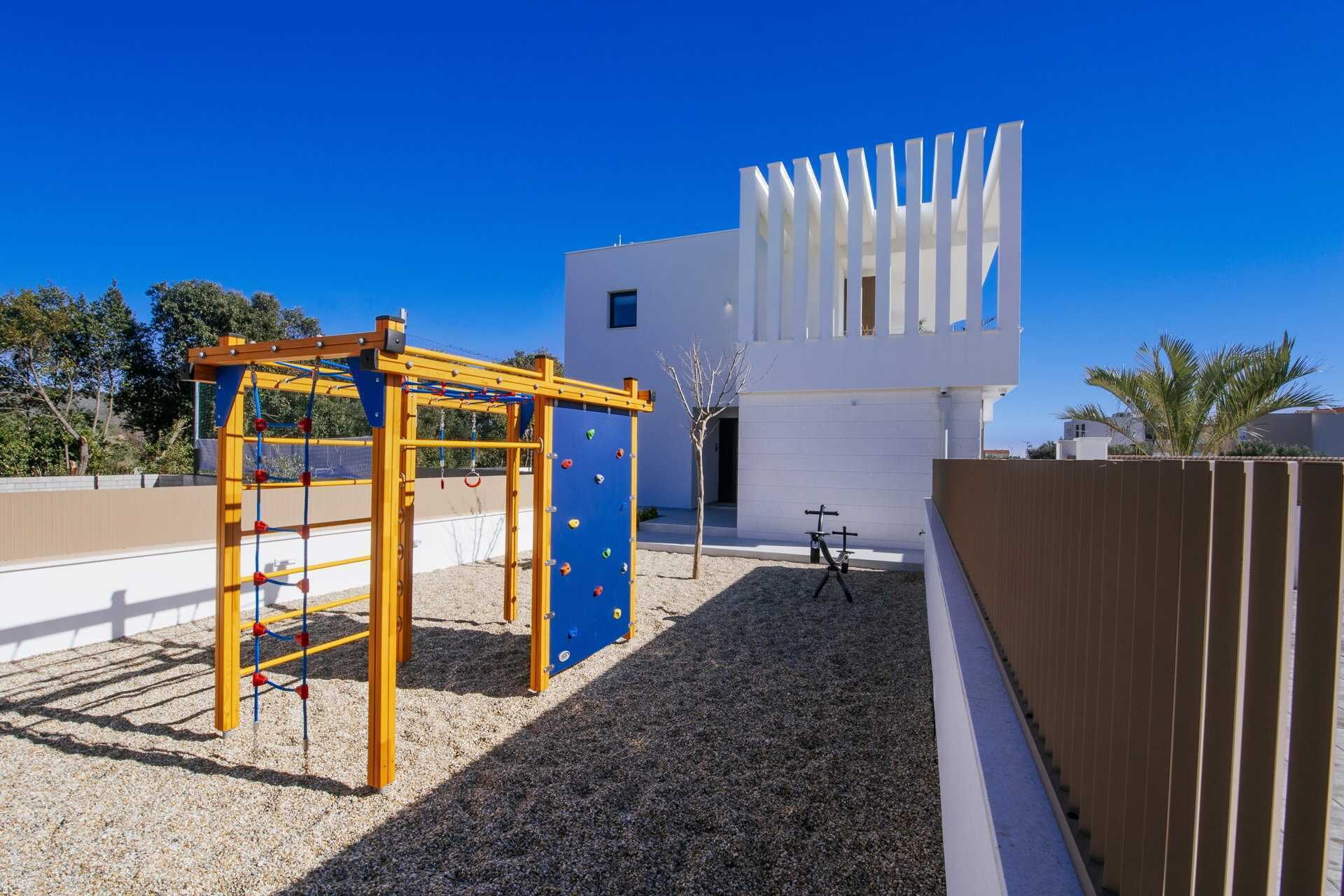Un parque infantil con estructuras para escalar y una bicicleta estacionada cerca de un edificio moderno.