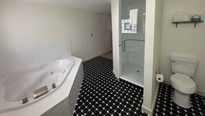 A bathroom with a white bathtub, a glass-enclosed shower, and a toilet. - Non-Smoking King With Jacuzzi - NKJ (Manitou Springs)