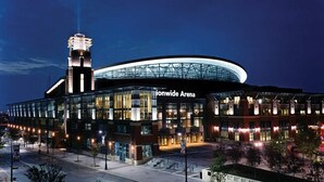 Eine moderne Arena mit einem markanten Turm und einer geschwungenen Glasfassade, genannt 'Ionwide Arena'.