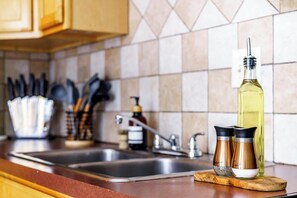 A kitchen counter with a sink, a bottle of oil, and two spice containers. - Short North & Downtown & OSU | Near High Street | Free Parking | 5,800+ Reviews (Columbus)