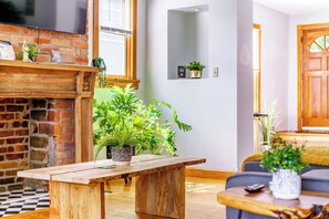A living room with a brick fireplace, a wooden coffee table, and potted plants. - Short North & Downtown & OSU | Near High Street | Free Parking | 5,800+ Reviews (Columbus)