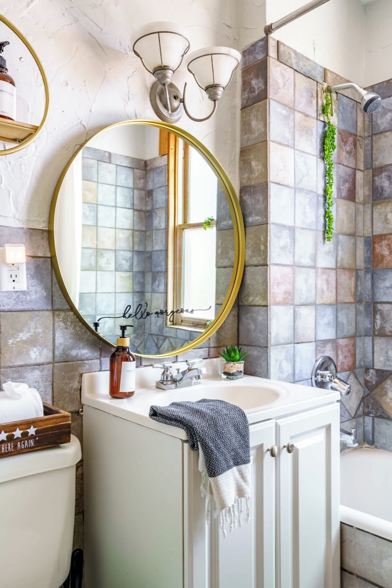 A bathroom with a round mirror, a sink, a toilet, and a shower area.