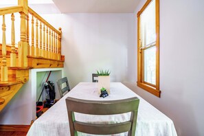 A dining area with a table, chairs, a potted plant, and a wooden staircase. - Short North & Downtown & OSU | Near High Street | Free Parking | 5,800+ Reviews (Columbus)