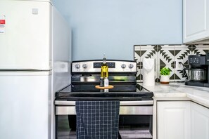A kitchen with a stove, a refrigerator, and a patterned backsplash. - Short North & Downtown & OSU | Near High Street | Free Parking | 5,800+ Reviews (Columbus)