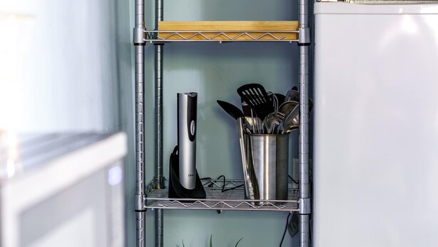 A kitchen with a stainless steel utensil holder, a coffee maker, and a potted plant on a shelf. - Short North & Downtown & OSU | Near High Street | Free Parking | 5,800+ Reviews (Columbus)