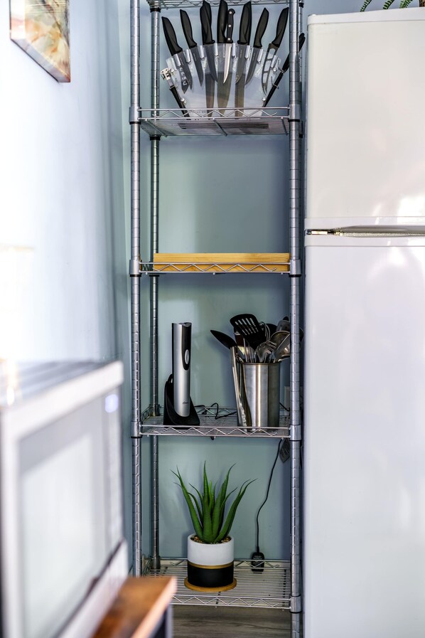 A kitchen with a stainless steel utensil holder, a coffee maker, and a potted plant on a shelf. - Short North & Downtown & OSU | Near High Street | Free Parking | 5,800+ Reviews (Columbus)