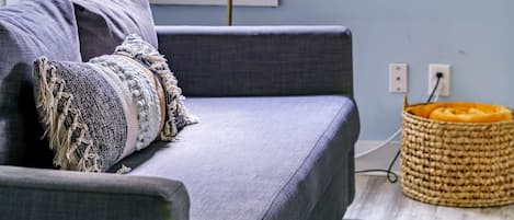 A room with a grey sofa, a decorative mirror, and a lamp.