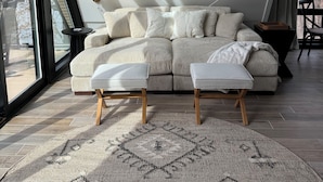 A modern living room with a sofa, ottomans, a rug, and a lamp.