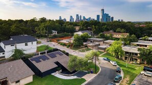 A residential area with houses, solar panels, and a city skyline in the background. - Austin Escape, Prime Location + Shared Yard Oasis Fairlawn Buyout by Avantstay (Austin)