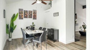 Un espace repas comprenant une table, des chaises, un ventilateur de plafond et des œuvres d’art murales.