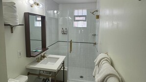 Et badeværelse med hvid vask, toilet og bruseområde.