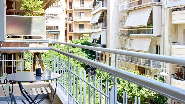 A balcony with a table and chairs, surrounded by multi-story buildings with balconies.