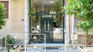 A building entrance with a green door, a number '18' sign, and a metal gate with heart-shaped designs.