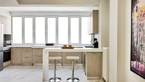 A modern kitchen with a central island, bar stools, and a large window.