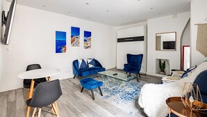 A modern living room with a sofa, chairs, a coffee table, and artwork on the wall.