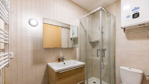 A bathroom with a glass-enclosed shower, a sink with a mirror above it, and a toilet.