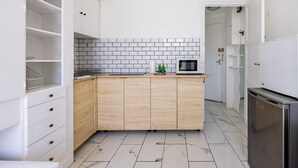 A modern kitchen with white cabinets, a tiled backsplash, and a microwave on the counter.