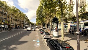 A street with cars, a pedestrian crossing, and trees lining the road.
