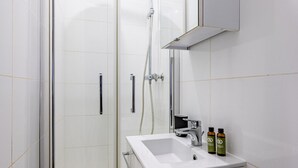 A modern bathroom with a glass-enclosed shower, a white sink, and a mirror above the sink.