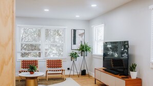 A modern living room with a TV, seating, and plants.