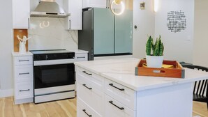 A modern kitchen with white cabinetry, a built-in oven, a stove, and a refrigerator.