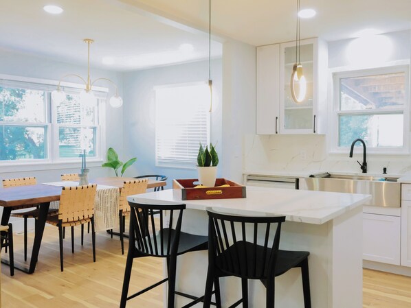 Una cocina moderna con armarios blancos, una isla grande e iluminación colgante.