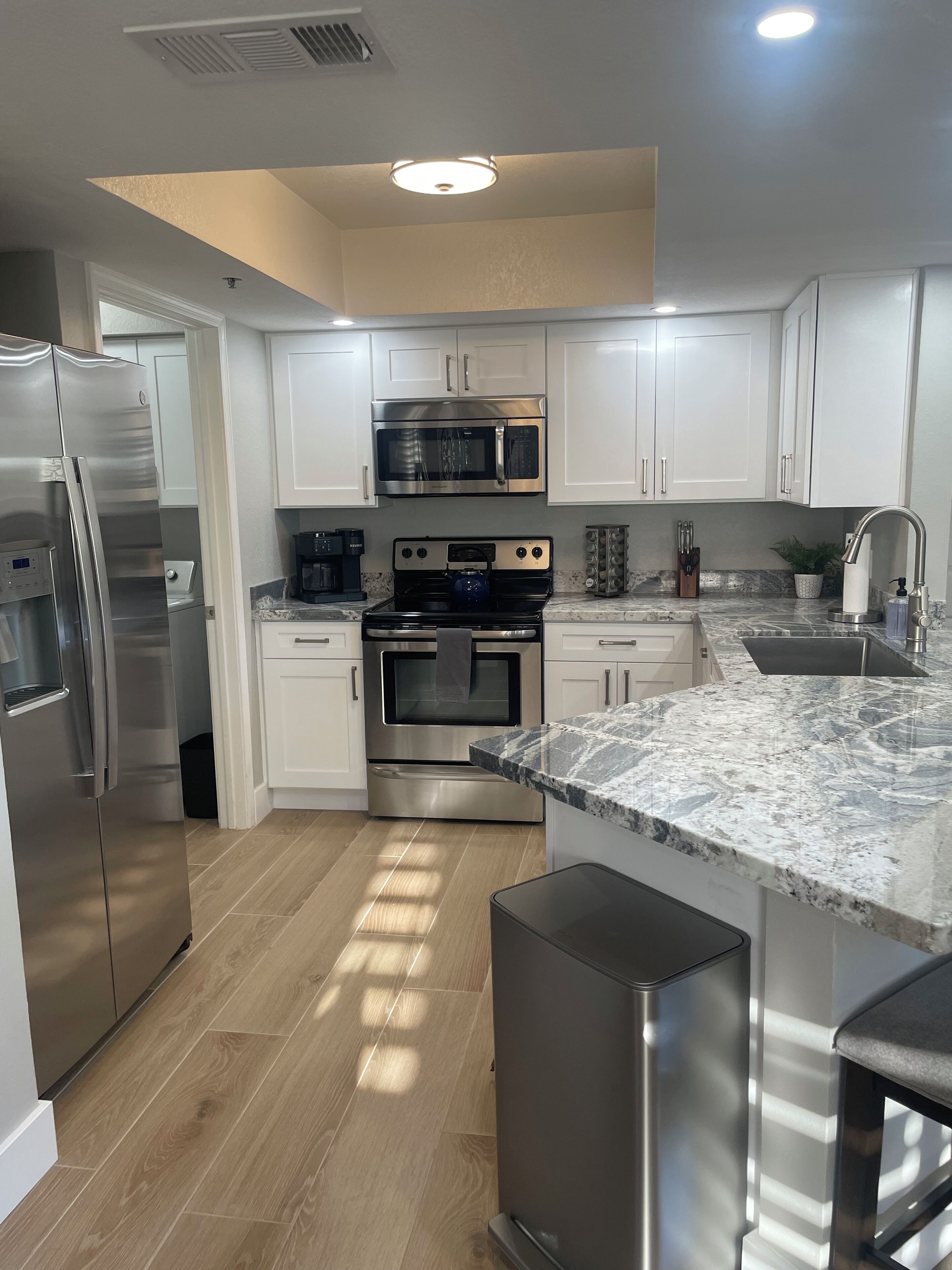 A modern kitchen with stainless steel appliances, white cabinetry, and a granite countertop.