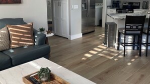 A modern living room with a sofa, coffee table, and a view into the kitchen area.