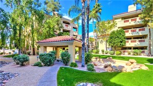 A courtyard with a gazebo, palm trees, and a pool area.